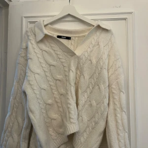 Vit kabelstickad tröja från Bikbok - Supermysig vit kabelstickad tröja från Bikbok med krage och v-ringning. Tröjan har lång ärm och en chunky känsla, perfekt för lager på lager. Snygg struktur och klassisk look som passar till allt. Aldrig använd och vill minnas att jag köpte den för 400 - 500kr!