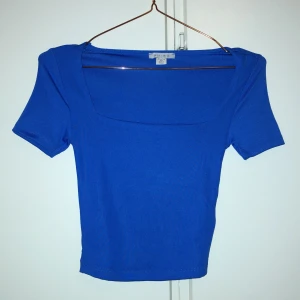Kungsblå topp med fyrkantig ringning  - Kungsblå topp från New yorker, Amisu i stretchigt material med korta ärmar och snygg fyrkantig ringning. Modellen är figurnära och croppad, perfekt till jeans eller kjol. Enkel och stilren design utan mönster eller detaljer. Aldrig använd endast testad så superbra skick!!!