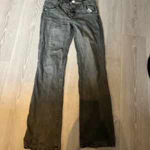 Grå bootcut jeans med broderade fickor - Säljer ett par grå jeans med bootcut-modell och snygga broderade detaljer på bakfickorna. Jeansen har klassisk femficksdesign och är tillverkade i ett mjukt jeansmaterial. Perfekta för dig som gillar en avslappnad men ändå stilren look.