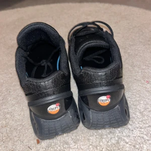 Nike Air Max DN svarta sneakers - Svarta Nike Air Max sneakers med mesh-ovandel och unika luftbubblor i sulan. Skorna har snörning och en sportig vibe, perfekt för dig som gillar streetwear. Diskret Nike-logga på sidan och Air Max-detaljer på plös och häl. Snygg och bekväm modell för vardagen.