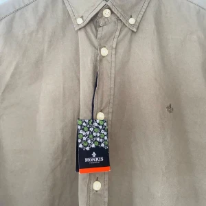 Beige skjorta från Morris Stockholm - Stilren beige skjorta från Morris Stockholm i bomull. Klassisk button-down krage, vita knappar och diskret broderad logga på bröstet. Perfekt för dig som gillar en clean och tidlös look.