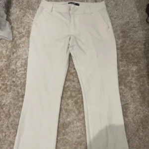 Vita kostymbyxor med bootcut - Vita kostymbyxor från bikbok, modellen Vera. Fint skick (förutom liten defekt längst ner vid kanten av byxorna, som förmodligen är enkelt att få bort med fläckborttagningsmedel om man har det!) 