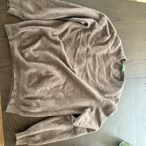 Brun stickad tröja från Benetton - Mysig brun stickad tröja från United Colors of Benetton. Rund hals och långärmad modell, perfekt för lager-på-lager. Materialet är mjukt och skönt, passar dig som gillar klassisk stil med enkel design.