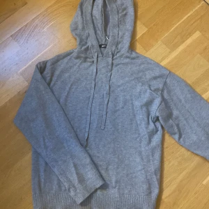 Grå hoodie i mjuk bomull - En basic grå hoodie från Gina Tricot i mjuk bomull. Tröjan har huva med snörning, långa ärmar och ribbade muddar. Perfekt för chill dagar och enkel att matcha med jeans eller leggings. Pris kan diskuteras💕