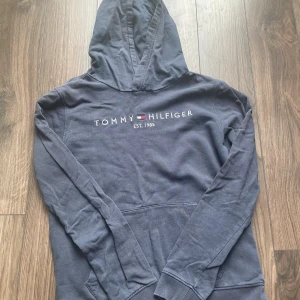 Blå hoodie från Tommy Hilfiger - Säljer nu min mörkblåa Hoodie från  Tommy hilfiger. Säljes pga den är för liten. Skick 6/10. Ett litet hål som man kan se på en av bilderna annars helt intakt. Legat i garderoben under senaste åren. Storlek 164cm. Hör gärna av er vid några funderingar. Mvh Alvin