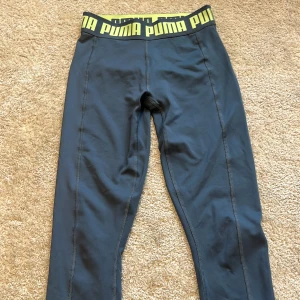Blåa leggings från Puma XS - Snygga blåa leggings från Puma i storlek XS. De har en bred resår i midjan med PUMA-logga i grönt och grått. Perfekta för träning eller chill, tillverkade i stretchigt syntetmaterial som sitter tajt och bekvämt. Kontakta för fler bilder