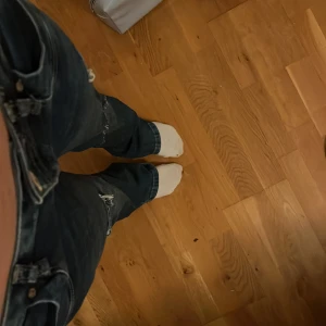 Mörkblå bootcut jeans från LTB - Säljer ett par mörkblå jeans från LTB med bootcut passform. Jeansen har slitna detaljer och hål på benen för en cool, avslappnad look. Klassisk femficksmodell med låg midja och dragkedja. 