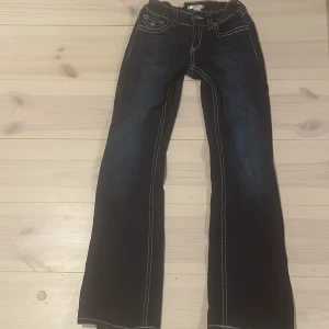 Mörkblå bootcut jeans Gina Tricot 158 - Snygga mörkblå jeans från Gina Tricot i storlek 158. Modellen har bootcut-ben och markerade vita sömmar som ger en cool kontrast. Klassisk femficksdesign och tillverkade i mjukt jeanstyg. Perfekta för dig som gillar en trendig och avslappnad stil.
