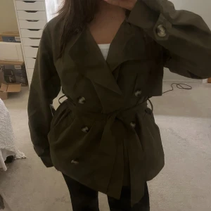 Trenchcoat - Supersnygg olivgrön trenchcoat💗Aldrig använd med prislappen kvar! Köpte på Vero Moda för 450kr. Skriv för mer bilder🤗
