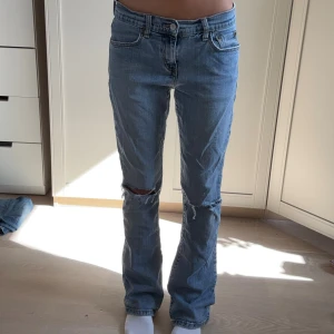 Levi's 516 bootcut jeans ljusblå - Säljer ett par Levi's 516 bootcut jeans i ljusblå denim. Modellen har klassisk femficksdesign, slitningar och hål på knäna för en cool vibe. Materialet är 99% bomull och 1% spandex för lite stretch. Perfekta om du gillar bootcut och vintagekänsla.