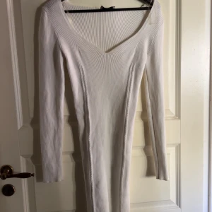 Vit ribbad långärmad klänning - Säljer en vit, ribbad klänning med lång ärm och v-ringad hals. Klänningen är figurnära och har en stilren, enkel design som passar perfekt för dig som gillar minimalistiskt mode. Från chiquelle💕