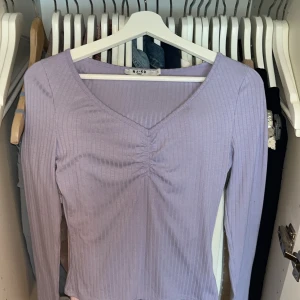 Ljuslila ribbad topp från NA-KD❤️ - Säljer en ljuslila långärmad topp från NA-KD i S men sitter även som Xs. Jätte söt och oanvänd❤️skriv för fler bilder