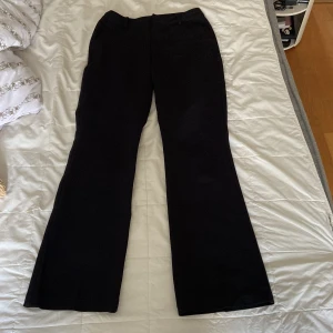 Svarta kostym byxor från BikBok - Svarta kostym byxor från BikBok i storlek 40. Byxorna har klassisk passform med utsvängda ben och hällor för bälte. Perfekta för en stilren look och lätta att matcha med olika toppar och skor.