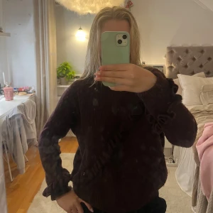 Vinröd  stickad tröja Twist & Tango - Mysig mörkbrun stickad tröja från Twist & Tango med volangdetaljer längs ärmar och över bröstet. 