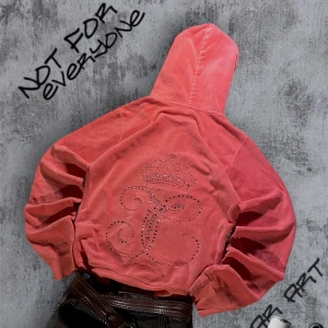 Juicy Couture Hoodie Med Rhinestones - Snygg Juicy Couture korallfärgad hoodie med dragkedja och huva. Perfekt för dig som vill sticka ut med stil. Små kristaller har lossnat men påverkar inte tröjan då det ser naturligt och snyggt ut! Storlek L, passar M/L