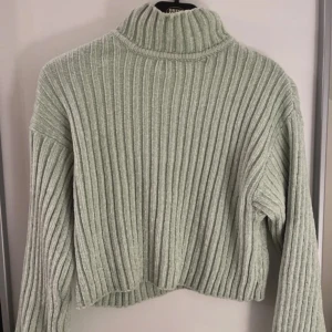 Ljusgrön ribbad polotröja - Supermysig ljusgrön polotröja med breda ribbade ränder. Tröjan är stickad och har en hög krage samt lång ärm. Perfekt för dig som gillar en chill och trendig look med lite croppad passform.