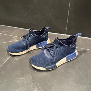 Adidas NMD R1 sneakers - Säljer nu ett par mörkblå Adidas nmd sneakers. Storlek 37 1/3. Skick 6/10 ganska så använda, men har betydligt mer att ge. Vid fler frågor eller funderingar tveka inte att höra av dig. Priset kan diskuteras!