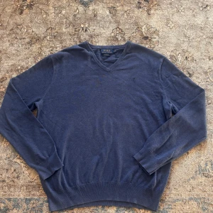 Ralph Lauren Tröja  - Mörkblå v-ringad tröja från Polo Ralph Lauren i mjuk pima bomull. Klassisk och stilren modell med långa ärmar och ribbade muddar vid ärmslut och nederkant. Perfekt för lager-på-lager och snygg till jeans eller chinos.