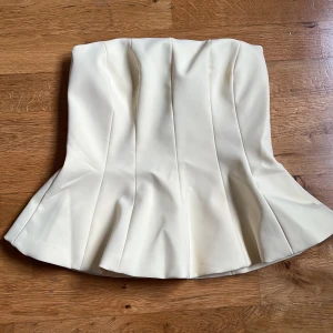 Gul axelbandslös topp med peplum - Säljer en gul topp från Zara i storlek S. Toppen är endast använd ca 1-2 gånger och är därmed i nyskick. Säljer då den inte kommer till användning.