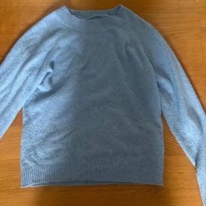 Ljusblå stickad tröja från Vero Moda - Mysig ljusblå stickad tröja från Vero Moda i storlek XS. Tröjan har en klassisk rund halsringning, ribbade muddar och är långärmad. Perfekt för lager-på-lager och chill dagar. Enkel och stilren design som passar till det mesta.