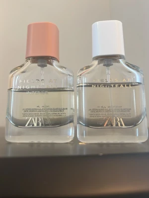 ZARA Fields at Nightfall parfymduo - Två parfymer från ZARA i serien Fields at Nightfall. Ena flaskan har en matt rosa kork och den andra en vit kork. Flaskorna är genomskinliga med minimalistisk design och text i silver och guld. Perfekt för dig som gillar stilrena och moderna dofter.