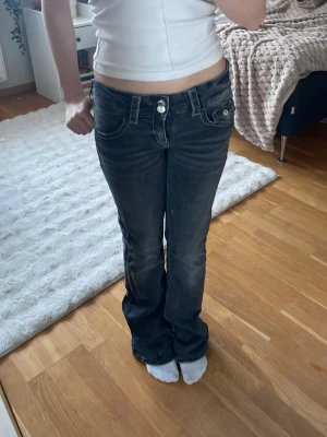 Svarta bootcut jeans med vita sömmar - Snygga svarta bootcut jeans med markerade vita sömmar och låg midja. Jeansen har två silver knappar. Perfekta för en trendig och avslappnad look. Säljer eftersom dem är för stora för mig. ❤️