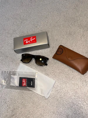 Svarta Ray-Ban solglasögon Wayfarer - Säljer ett par snygga Ray-Ban solglasögon i väldigt fint skick, perfekta för grisch/prisvärd deal 💥 Kommer med original fodral, putsduk och box som syns på bilderna. En riktig klassiker som passar till allt och funkar lika bra till vardag som sommar. Jag är aktiv på Plick och svarar snabbt, fraktar direkt samma dag eller senast nästa dag så du slipper vänta. Säker och smidig affär, bara att köpa direkt innan de ryker 👌