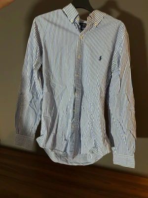 Blårandig skjorta från Polo Ralph Lauren - Klassisk blårandig skjorta från Polo Ralph Lauren. Perfekt för en stilren och avslappnad look.