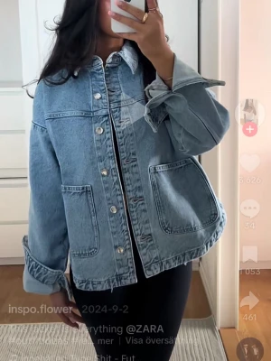 Ljusblå jeansjacka från ZARA - Trendig ljusblå jeansjacka från ZARA med klassisk krage, stora framfickor och silvriga knappar. Jackan har en avslappnad passform och är tillverkad i denim. Perfekt för att lyfta vilken outfit som helst.