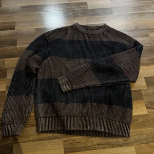 Randig brun och svart stickad tröja - Stickad tröja från Pull & Bear med ränder i brunt och svart. Tröjan har rundad hals och är i storlek M. Perfekt för en avslappnad och unik stil. Priset kan diskuteras👍