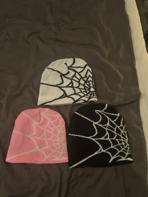 Mössor med spindelnätsmönster - Tre coola mössor i svart, vitt och rosa med stickat spindelnätsmönster. Perfekt accessoar för att addera lite edge till din stil.  1 för 100kr alla 3 för 250kr
