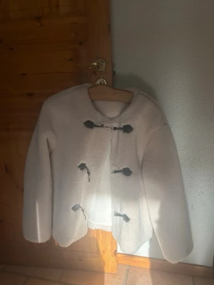 Beige teddyjacka  - Mysig beige teddyjacka med tre svarta toggleknäppningar framtill och fickor 🥰 Från Gina tricot i storlek M.