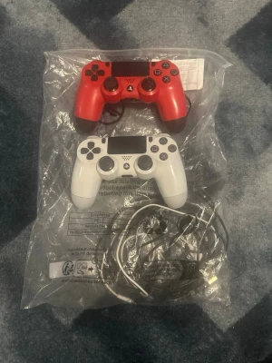 Två DualShock 4 handkontroller PS4 - Bundle of 2 official PlayStation 4 DualShock 4 wireless controllers.  Includes: 	•	1x Red DualShock 4 controller 	•	1x White DualShock 4 controller  Condition: 	•	Used, in good working condition 	•	Fully tested – all buttons, sticks and triggers work 	•	No stick drift 	•	Normal signs of use from regular gaming (see photos)  💰 Pricing options: 	•	249 kr for 1 controller 	•	449 kr for both controllers  If you’re interested in buying just one, please message me first.