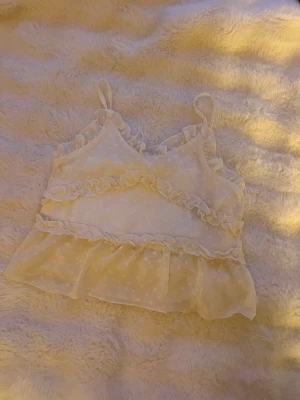 Vit volangprydd linnetopp H&M - Supersöt vit linnetopp från H&M med tunna axelband, volangdetaljer och diskret prickigt mönster. Toppen är lätt och luftig och perfekt för varma dagar. Hyfsat ny och har använts varsamt🩷i storlek 158