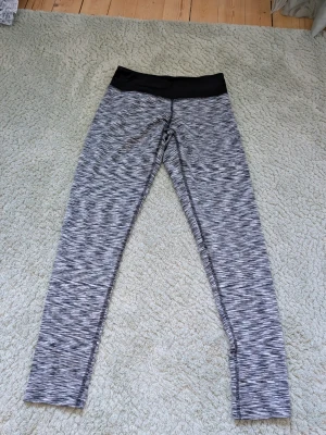 Gråmelerade träningstights från soc  - Snygga gråmelerade träningstights med svart midjeresår. Tightsen har en åtsittande passform och är perfekta för gymmet eller löprundan. Tillverkade i ett stretchigt material som ger bra rörelsefrihet.
