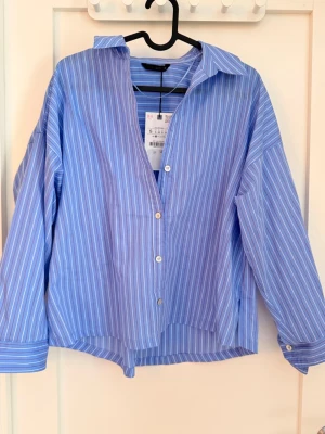 Blå randig skjorta från Zara - Snygg blå skjorta från Zara med vita och röda ränder. Helt ny, pris lapp kvar