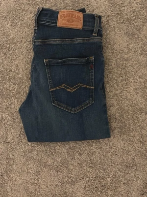 Replay Anbass blå jeans herr - Säljer ett par Replay Anbass jeans i mörkblå tvätt med snygg tvätt och klassiska kontrastsömmar. Modellen på bilden är 175