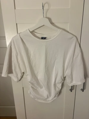 Vit topp - Säljer en vit croppad topp från Gina Tricot med korta ärmar och rund hals. Toppen har en enkel och clean look, perfekt till jeans eller kjol. Tillverkad i mjuk bomull för skön känsla hela dagen.