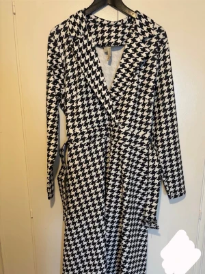 Klänning  - Stilren svartvit klänning med klassiskt mönster och knytskärp i midjan. Storlek 44/46