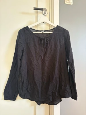 Svart blus med knut från Bik Bok - Svart blus från Bik Bok med rund halsringning och knytband framtill. Långärmad modell med avslappnad passform.