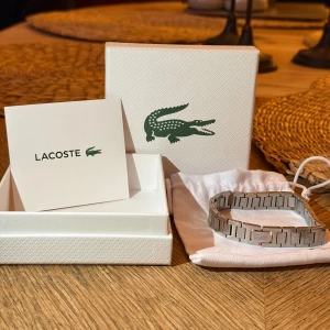 Lacoste silverfärgat armband - Snyggt armband från Lacoste i silver. Kommer i originalförpackning med tillhörande tygpåse och kort. Fick som julklapp men inte använt, så skicket är som nytt. Perfekt för dig som söker något nu inför varmare väder. Skriv vid funderingar eller prisförslag☺️☺️