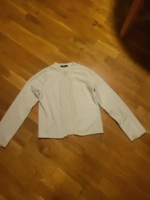 Kofta från Gina Tricot - Mysig beige kofta från Gina Tricot med rund halsringning och ribbade kanter. Koftan har en enkel knapp framtill och är långärmad, perfekt för lager på lager. Passar till många olika stilar och är lätt att matcha.