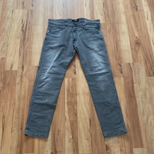 Replay Anbass grå jeans - Snygga grå Replay Anbass jeans i rak modell. Klassisk femficksdesign, diskreta sömmar och bekväm passform. Jeansen är tillverkade i bomull med en touch av stretch för extra komfort. Perfekta för dig som gillar stilrena och enkla jeans. W36/ L32