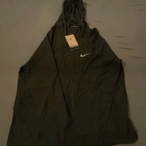 Svart Nike vindjacka med huva - Svart vindjacka från Nike med vit logga på bröstet.
