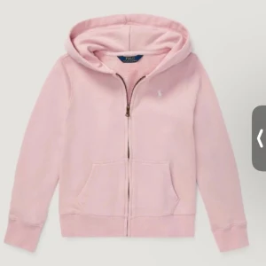 Ljusrosa hoodie från Polo Ralph Lauren - Säljer en ljusrosa hoodie från Polo Ralph Lauren med dragkedja framtill och klassisk huva. Tröjan har långa ärmar, känguruficka och diskret broderad logga på bröstet. Perfekt för en chill och avslappnad stil.
