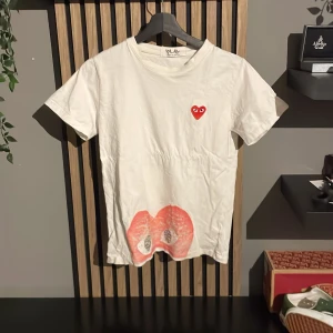 Vit Comme des Garçons Play t-shirt - Säljer en vit t-shirt från Comme des Garçons Play.passar dig som är nånstans mellan 155-165, hjärtat där ners på magen är lite slitet men inget man dirket tänker på ifall man är kräsen, men där av priset!😁