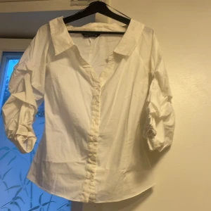 Vit skjorta med puffärm från Zara - Snygg vit skjorta från Zara Woman med bred krage och puffiga trekvartsärmar. Skjortan har knappar framtill och är tillverkad i bomull. Passformen är normal och materialet känns mjukt och fräscht. Perfekt för dig som gillar stilrena plagg med en twist. Skjortan kan passa dig också som har storlek S.