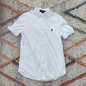 Kort armad Ralph Lauren skjorta  - Säljer en kortarmad Ralph Lauren skjorta som passar inte mig längre. Jag har bara haft på den en gång och den har inga hål. Skjortan är perfekt för varmt sommar väder när du vill klä upp dig. 