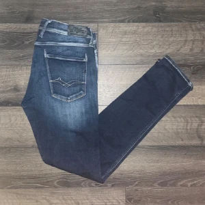 Replay jeans  - Säljer ett par Replay Anbass jeans i mörkblå tvätt med snygga slitningar och kontrastsömmar. Modellen är slim fit. Jag vet ej om hålet är defekt heller styling det får ögat själv avgöra :) som det syns har en söm gått upp lätt på bakfickan. midja 41cm, längd 108cm. JAG SKICKAR EJ FLER BILDER NÄR JAG BÄR JEANSEN! för storleksguide hänvisar jag till måtten och för bättre inblick i passformen rekommenderar jag att googla på modellnamnet :) S3