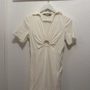 Vit kortklänning - Superfin vit kortklänning från Zara med djup v-ringning och ringdetalj framtill. Klänningen har krage, korta ärmar och är gjord i linneamatrial.🩷